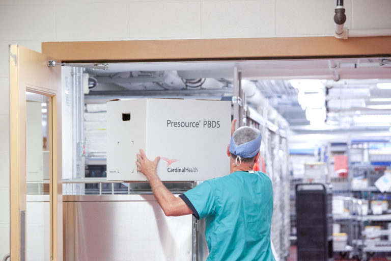 In a hospital room, a man is seen in the hallway with a PBDS box, suggesting medical supplies.