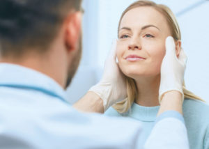 Woman receiving facial examination from doctor.