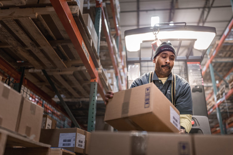 A man in a warehouse, diligently working amidst numerous boxes, ensuring efficient operations.