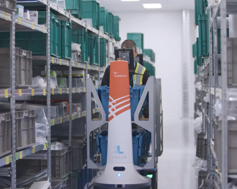 A working navigating a warehouse on a machine, efficiently moving through the aisles to complete tasks.